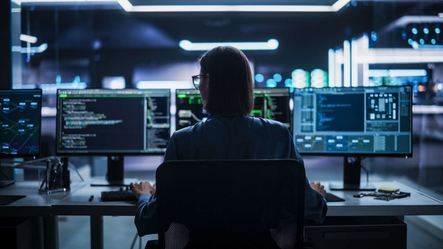 Back View of Female Telecommunications Manager Working in Research and Development Facility on a Desktop Computer in Modern Office. Focused Software Engineer Updating Server System Database